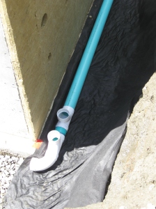 Landscape fabric under drainage pipe. This is the southeast corner, the highest point for the drainage system; the two openings are for tall vertical pipes that can be used for cleaning any stoppages.