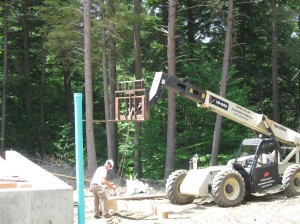 Tim helping attach a beam to the telehandler. This wonderful machine can turn on a dime, has a forklift (to which a chain can be attached, as here), on an extendable arm.