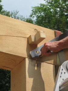 Here Silas is trimming off the end of a peg (the whole frame is held together with wooden pegs), and you can see the two wedges (one from each side) that tighten up the scarf joint.